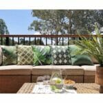Several jungle inspired green outdoor cushions covers on brown sofa