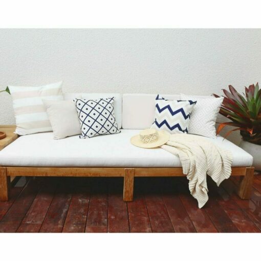 Beige and navy cushions with various patterns on wooden daybed.