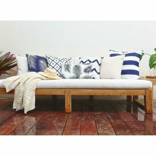 Navy and white outdoor cushions in stripe, chevron, diamond and floral patterns on top of white and wooden daybed.