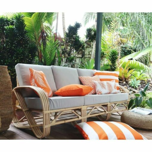 Bright orange outdoor cushions in various patterns on top of grey rattan sofa