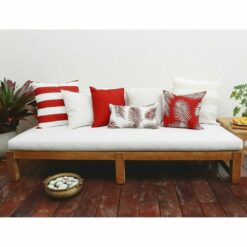 Red outdoor cushion covers in stripe, diamond and leaf patterns on top of wooden daybed.