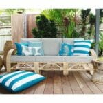 Teal and white outdoor cushion in diamond, leaf, stripe patterns on rattan sofa