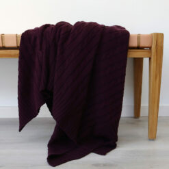An image of a purple knitted throw draped over a stool