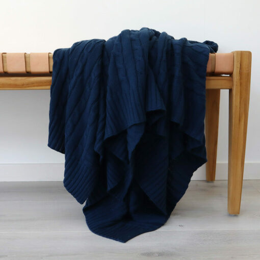 An image of a royal blue knitted throw draped over a stool