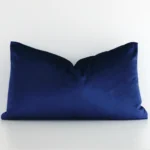 Royal blue velvet cushion cover features prominently against a white wall. It is a rectangular design and has a solid colour finish.