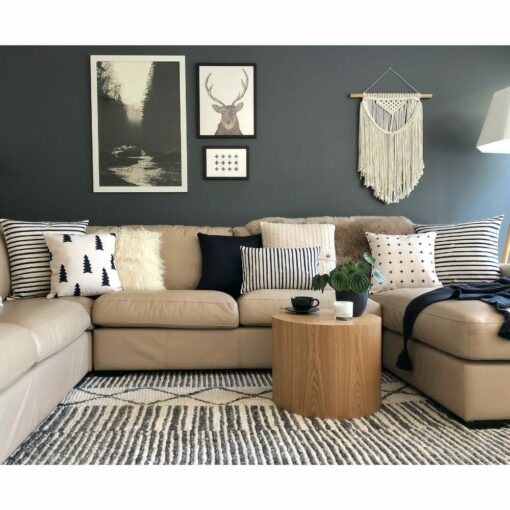 Scandi-themed living room with beige leather sofa, round wooden side table and cushions in varying prints, fur and knit material