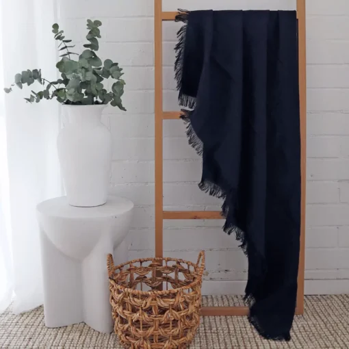 A black linen throw gracefully adorns a wooden rack.