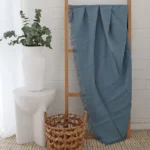 A wooden rack hosts a blue linen throw, its folds flowing gracefully.