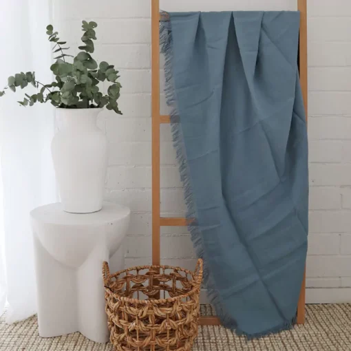 A wooden rack hosts a blue linen throw, its folds flowing gracefully.