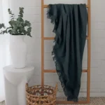 A wooden rack elegantly displays a green linen throw, its fabric gracefully draped.