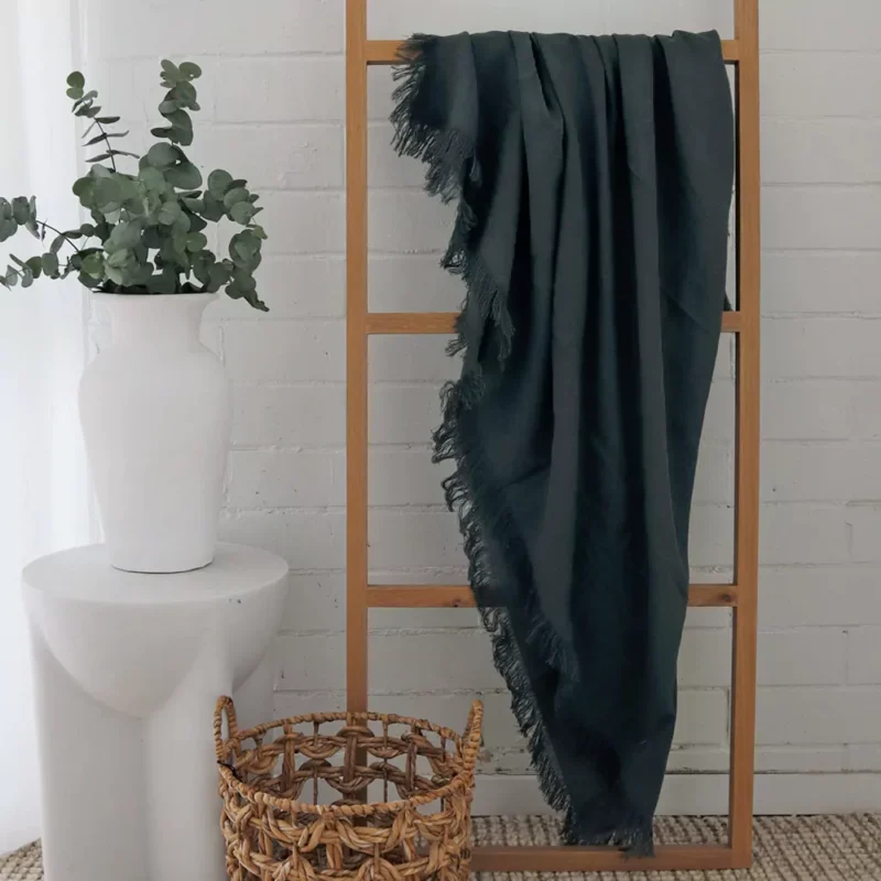 Sofia Green Linen Throw - TH811 A wooden rack elegantly displays a green linen throw, its fabric gracefully draped.