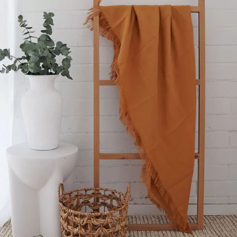 A wooden rack is creatively adorned with a mustard linen throw.
