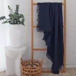 A wooden rack displays a navy linen throw.