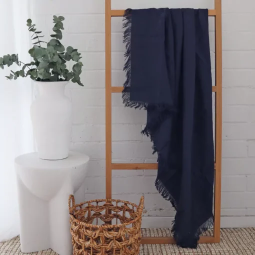 A wooden rack displays a navy linen throw.
