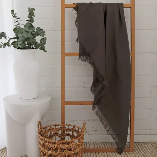 An olive linen throw hangs on a wooden rack.