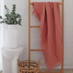 A wooden rack is adorned with a pink linen throw.