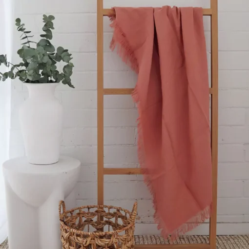 A wooden rack is adorned with a pink linen throw.