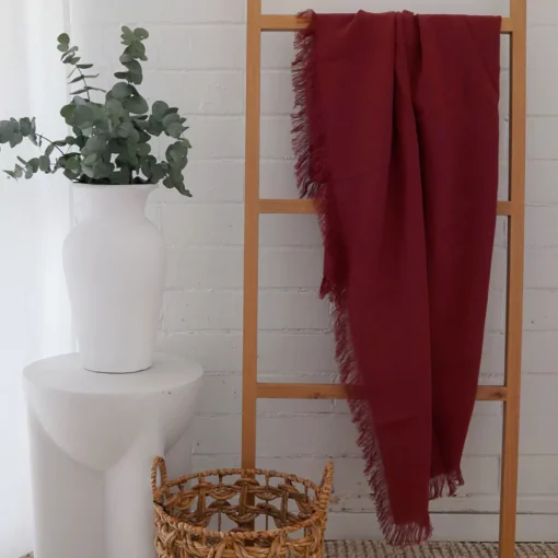 A wooden rack supports a rust linen throw, its rich hue and inviting texture infusing the space with grace.