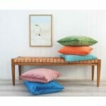 Colourful velvet cushion covers on wooden seat against a wall art