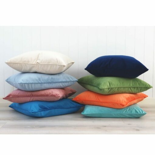 Stacks of colourful velvet cushions against a white wall