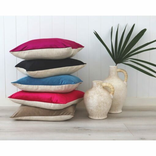 A stack of dark-colored velvet linen cushions against a white wall