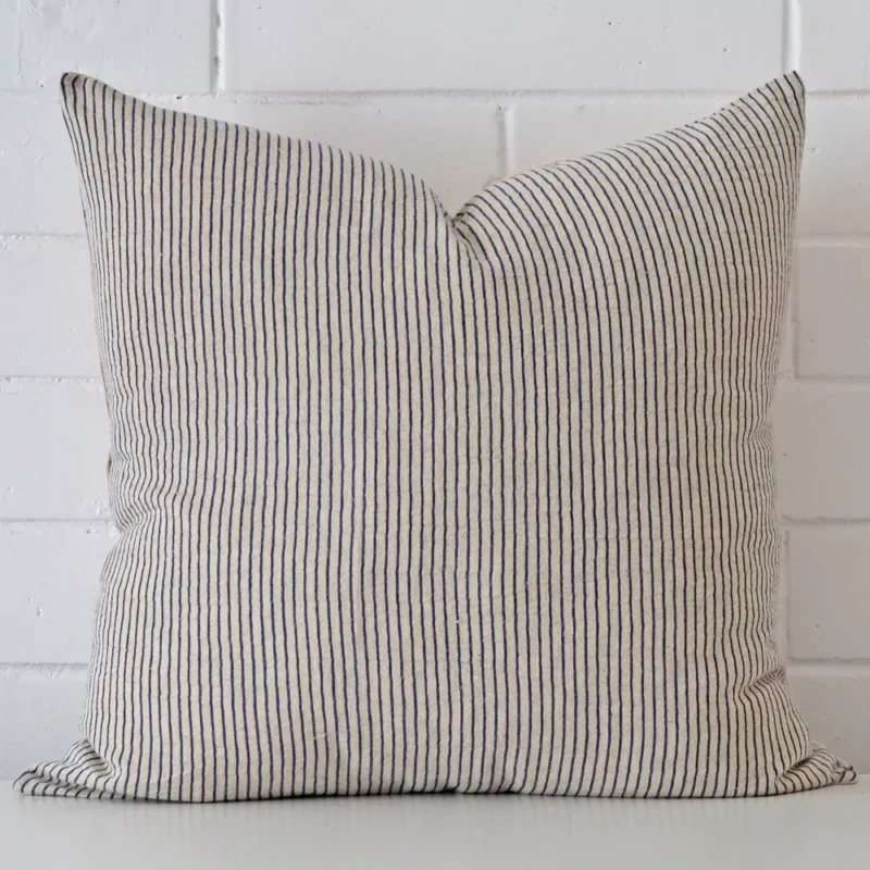 agnes-striped-designer-cushion-cover-art107-55 Striped cushion positioned in front of a brick wall. It has large dimensions and is made from a designer material.