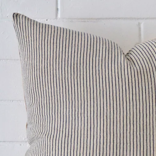 A zoomed in photo of the corner of a striped cushion that has designer fabric and a large size.