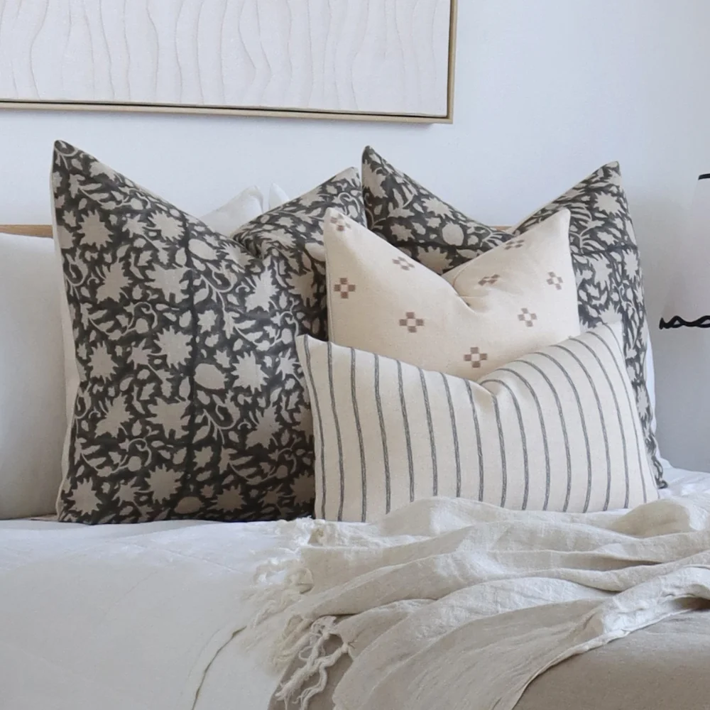 An airy bedroom scene with designer cushion sets layered on bed.