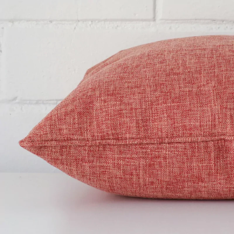 An auburn cushion positioned on its back panel. The shot shows a lateral view of the linen fabric and its square size.