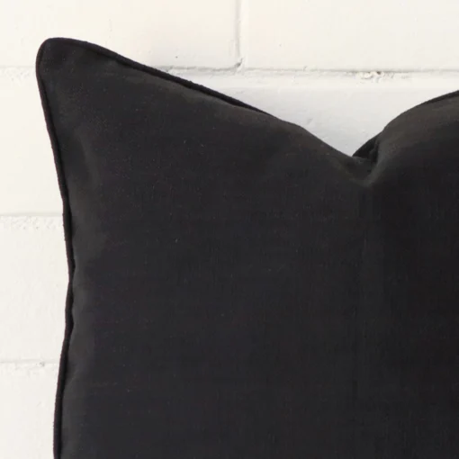 A close up shot showing the top left side of this square linen cushion cover. The black tone is magnified.