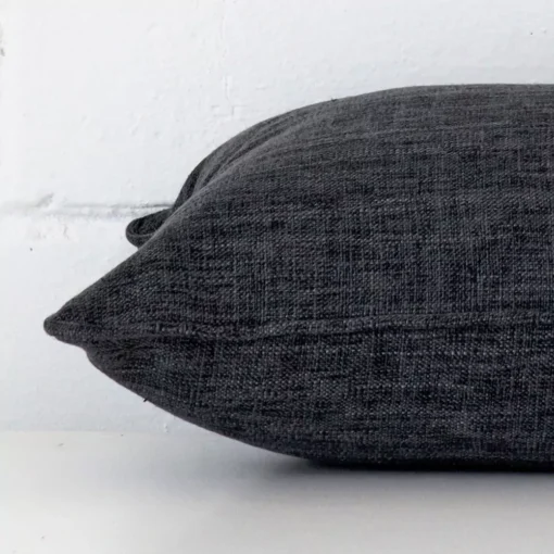 A charcoal cushion positioned on its back panel. The shot shows a lateral view of the linen fabric and its rectangle size.