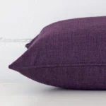 Rectangle cushion in plum colour laying flat. The viewpoint highlights the seams of the linen fabric.