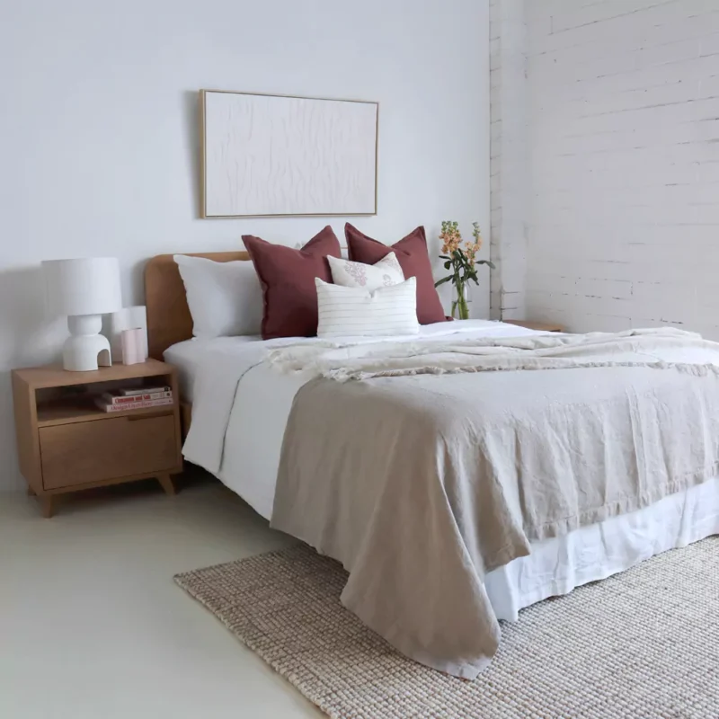 A wooden bed covered in crisp white bedding is beautifully accessorised with the four-piece Ali bed cushion set.