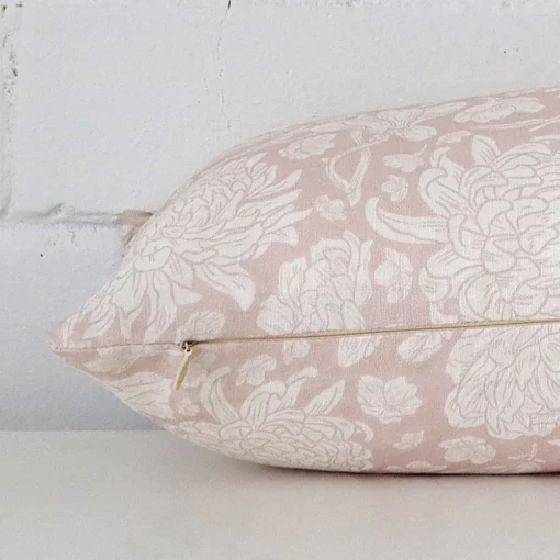 A floral light pink cushion cover is laid flat. This angle shows the side of the linen fabric and its rectangle shape.