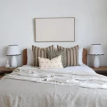 A bed featuring a wooden headboard adorned with the Amaro cushion set, highlighting four designer cushions.