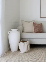 A corner of a grey sofa is styled with the two designer cushions from the Amaro sofa cushions set.