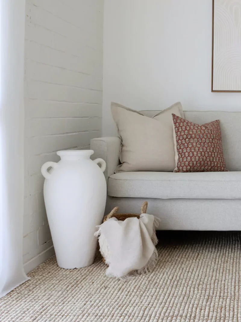 A corner of a grey sofa is styled with the two designer cushions from the Amaro sofa cushions set.