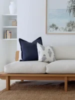 Two of the set of 5 cushions on sofa against a white wall.