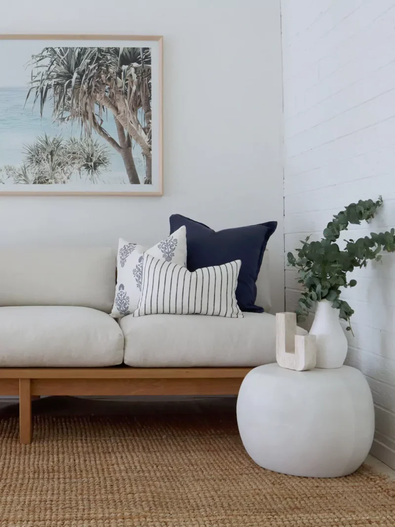A light-coloured seat with three premium sofa cushion covers styled in the corner of it.