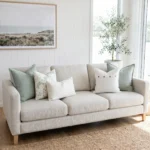 Five cushions featuring sage linen, a botanical print, with button and boucle lumbar details, on a sofa.
