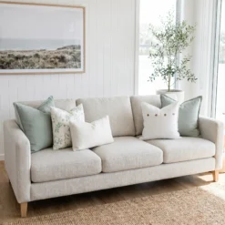 Five cushions featuring sage linen, a botanical print, with button and boucle lumbar details, on a sofa.