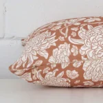Rectangle floral cushion in terracotta colour laying flat. The viewpoint highlights the seams of the linen fabric.