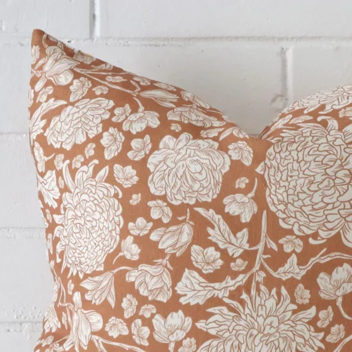 A magnified shot of a floral linen cushion cover in a square size and a terracotta colour.