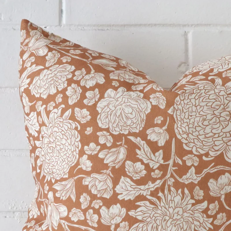 A magnified shot of a floral linen cushion cover in a square size and a terracotta colour.