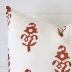 A close up shot showing the top left side of this square linen cushion cover. The terracotta tone and patterned design are magnified.
