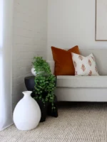 A light grey sofa with terracotta-coloured cushions resting on one of its corners.