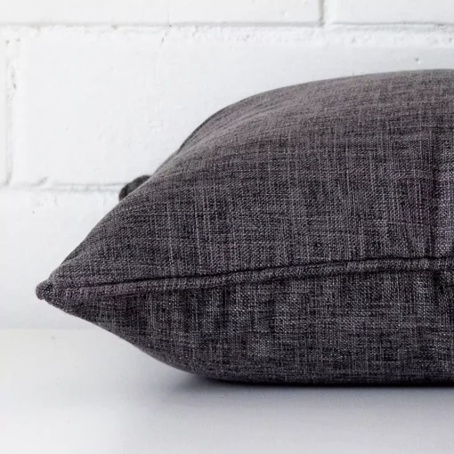 Side shot showing the seam of this square grey cushion that is made from linen material.