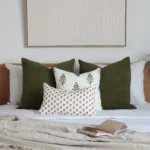 4 bed cushions from the Ava set are under a wooden-framed wall decor.