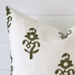 A close up image of this patterned square cushion. The image shows details of its linen fabric and olive green colour.