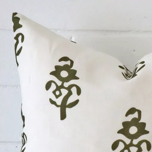 A close up image of this patterned square cushion. The image shows details of its linen fabric and olive green colour.